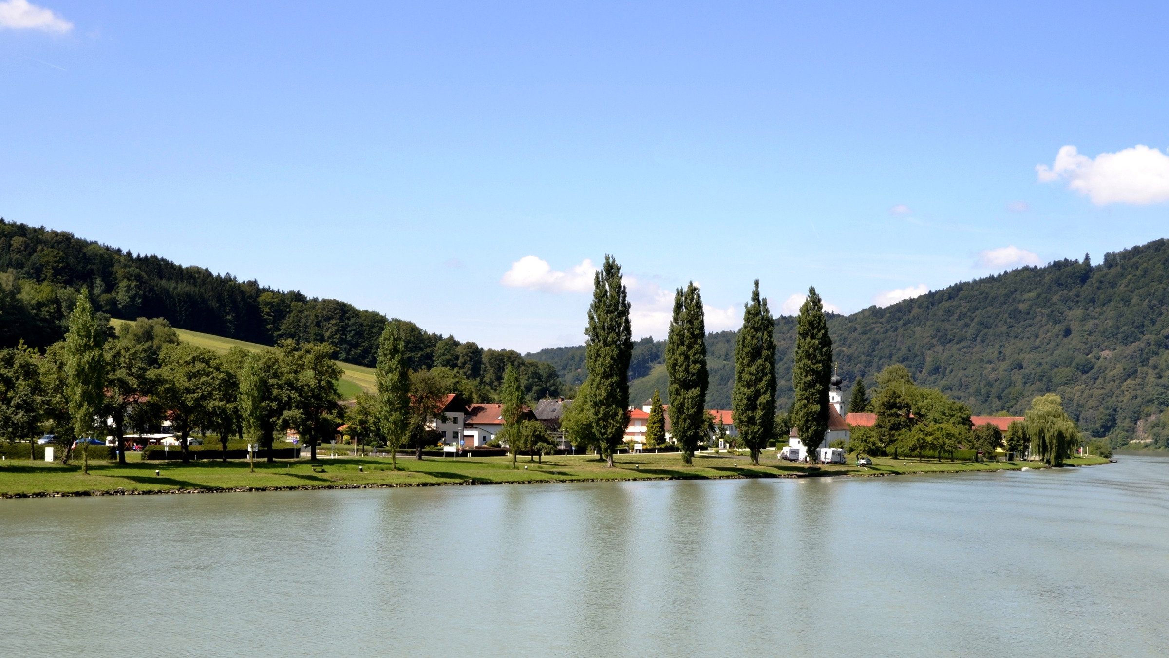 Breiter Blick auf die Donau mit Ufer und österreichischer Ortschaft